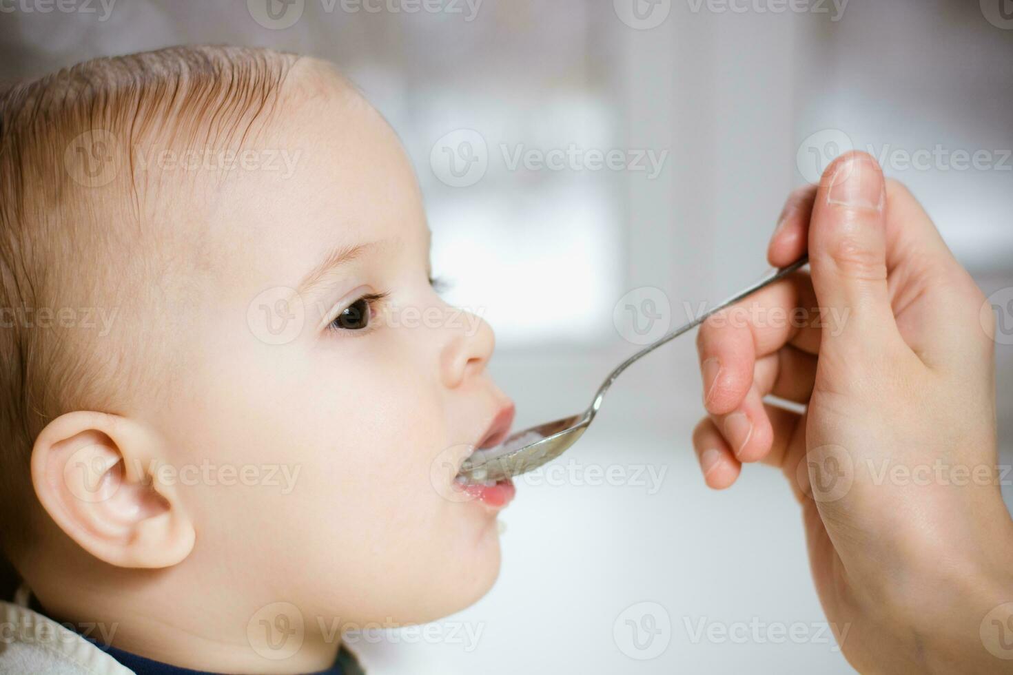 Mother gives baby food from a spoon photo