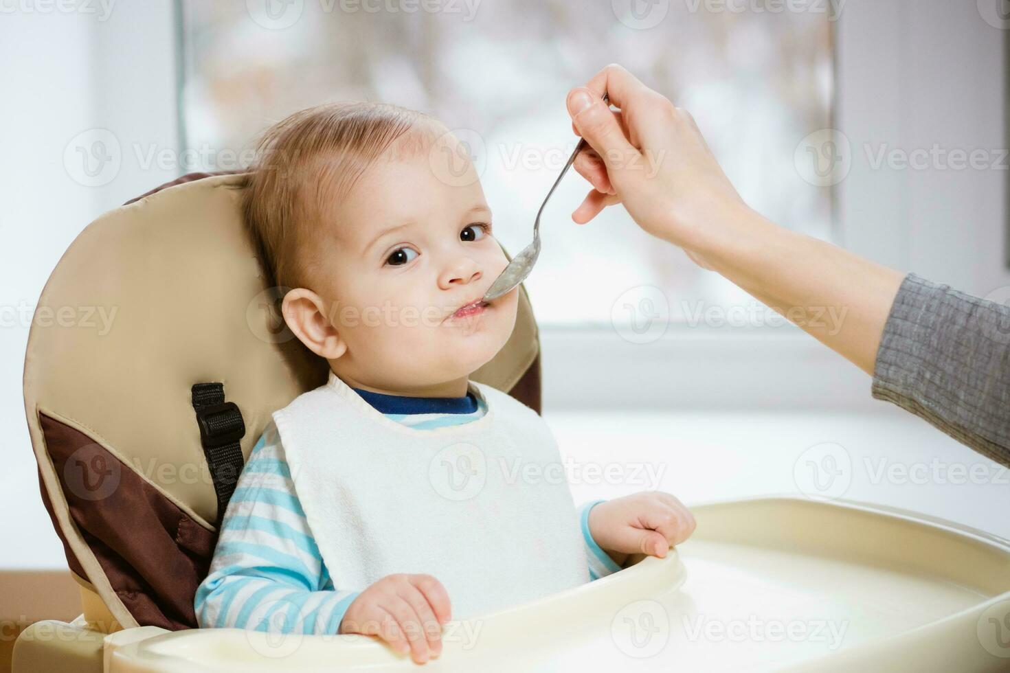 Mother gives baby food from a spoon photo