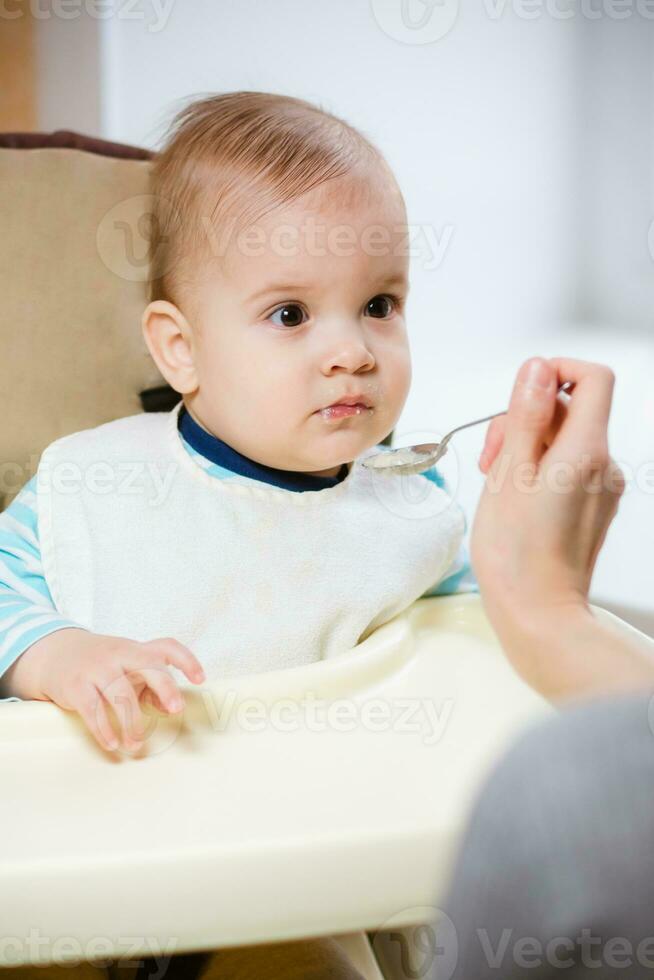 Mother gives baby food from a spoon photo