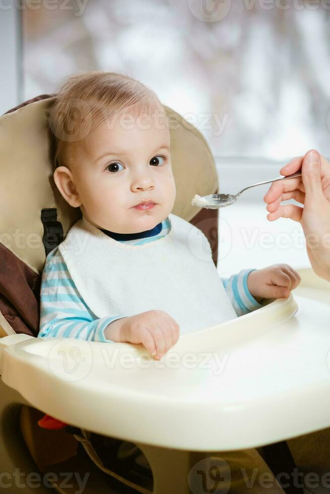 Mother gives baby food from a spoon photo