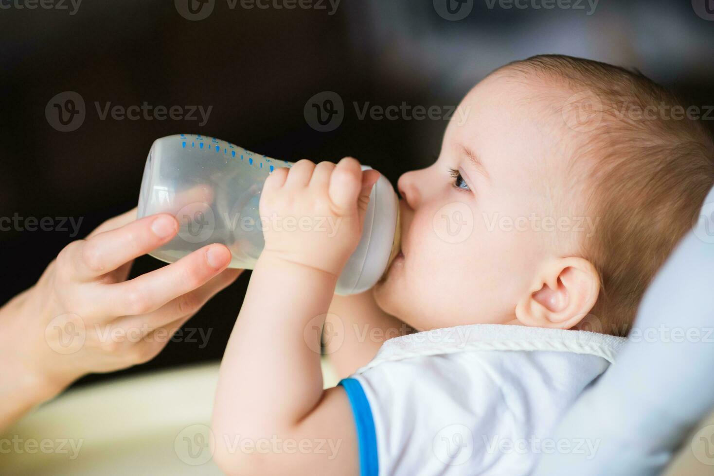 Mother feeds baby from a bottle of milk photo