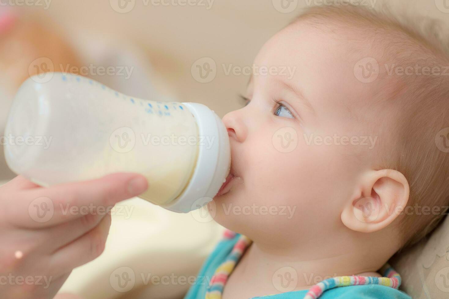 Mother feeds baby from a bottle of milk photo