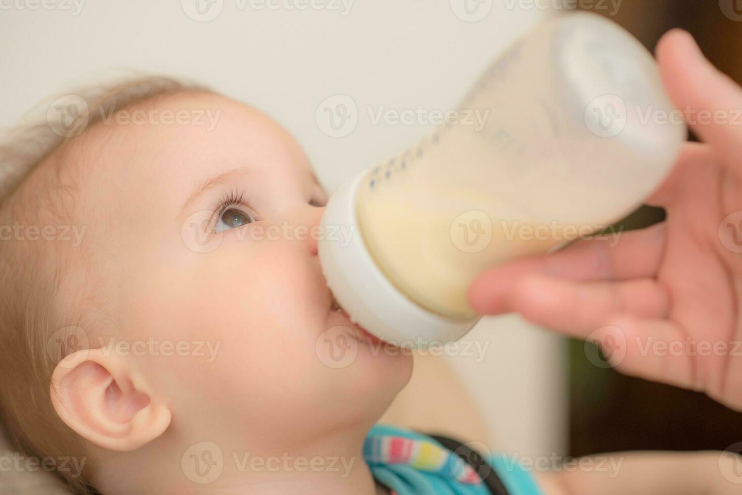 Mother feeds baby from a bottle of milk photo