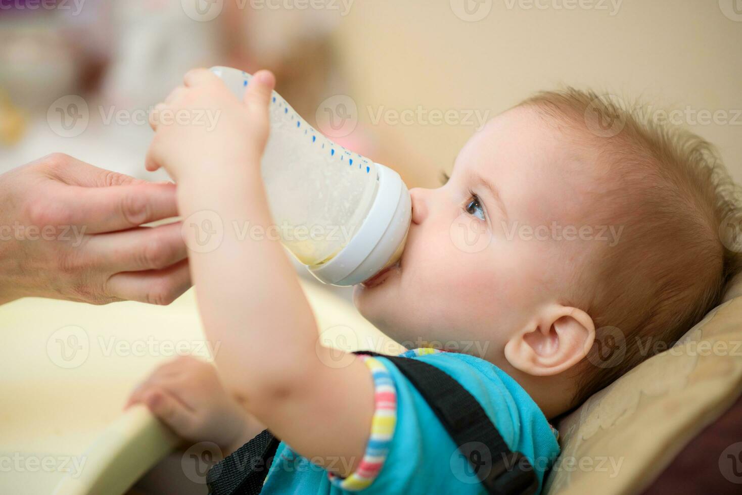 Mother feeds baby from a bottle of milk photo