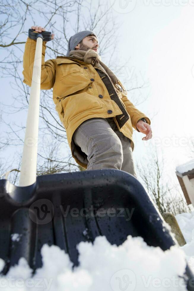 young man shoveling snow near a small wood photo