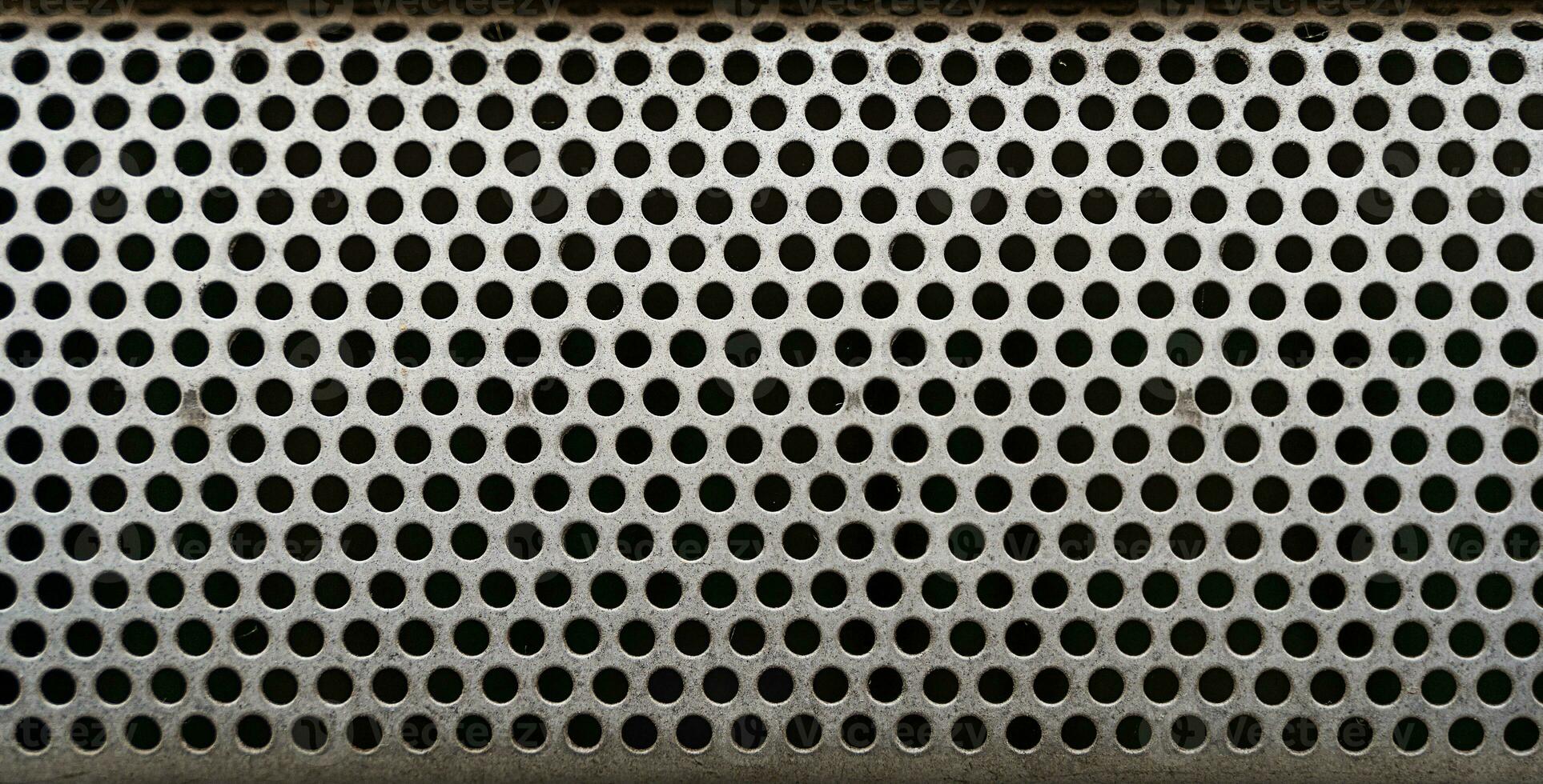 close up of a metal grate with small round holes - background for use as a texture photo