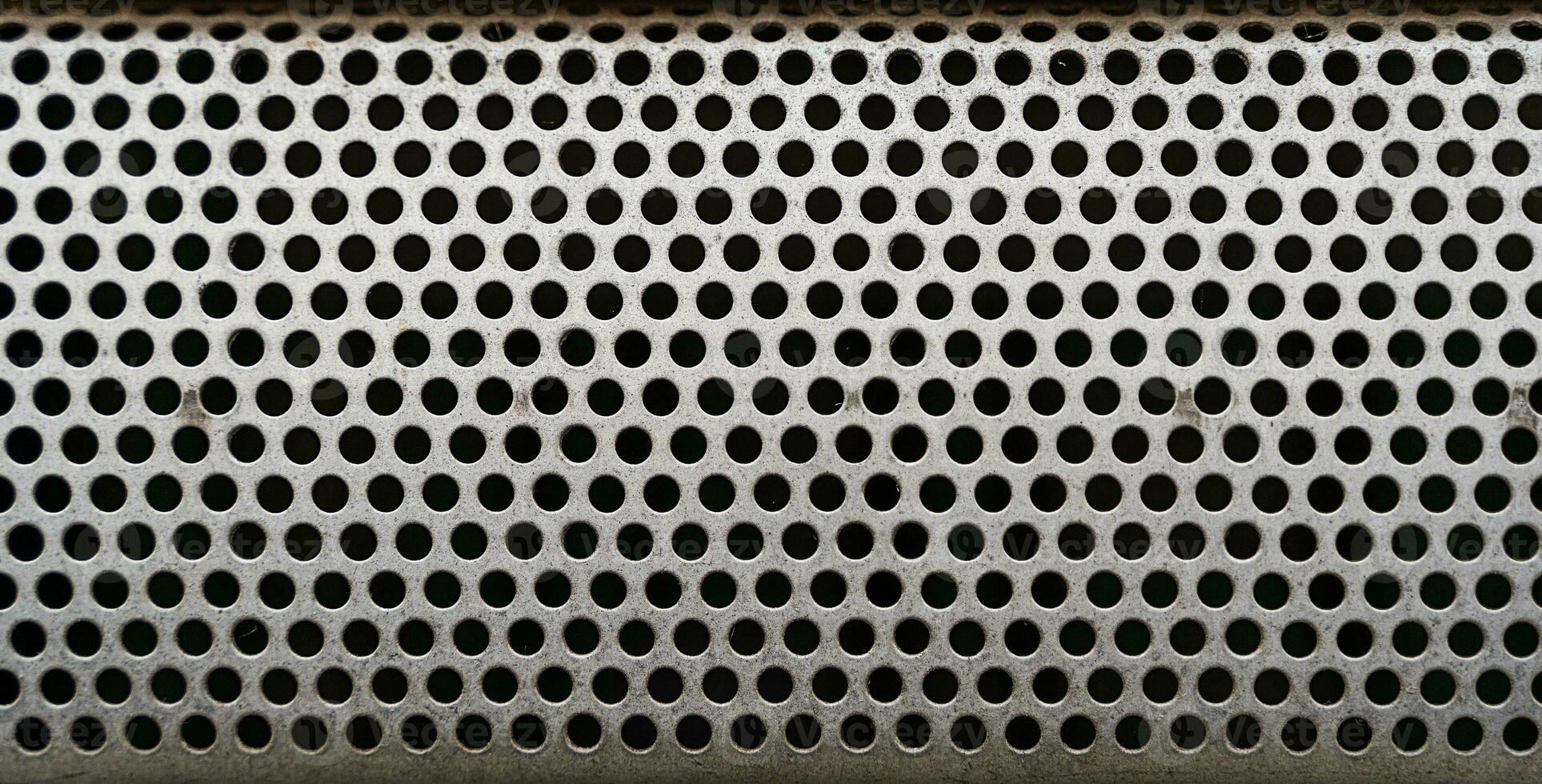 close up of a metal grate with small round holes - background for use as a texture photo