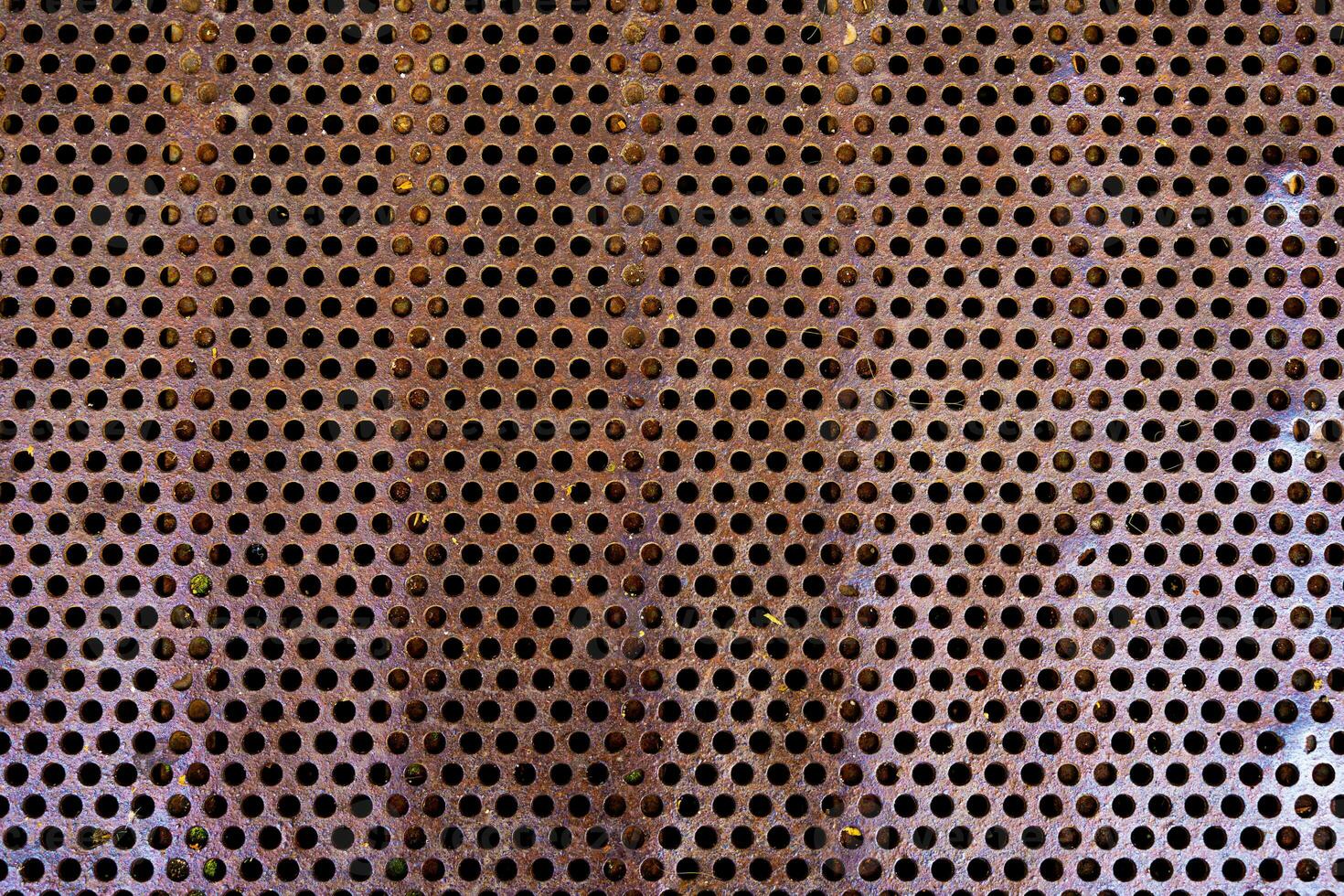 close up of a metal grate with small round holes - background for use as a texture photo
