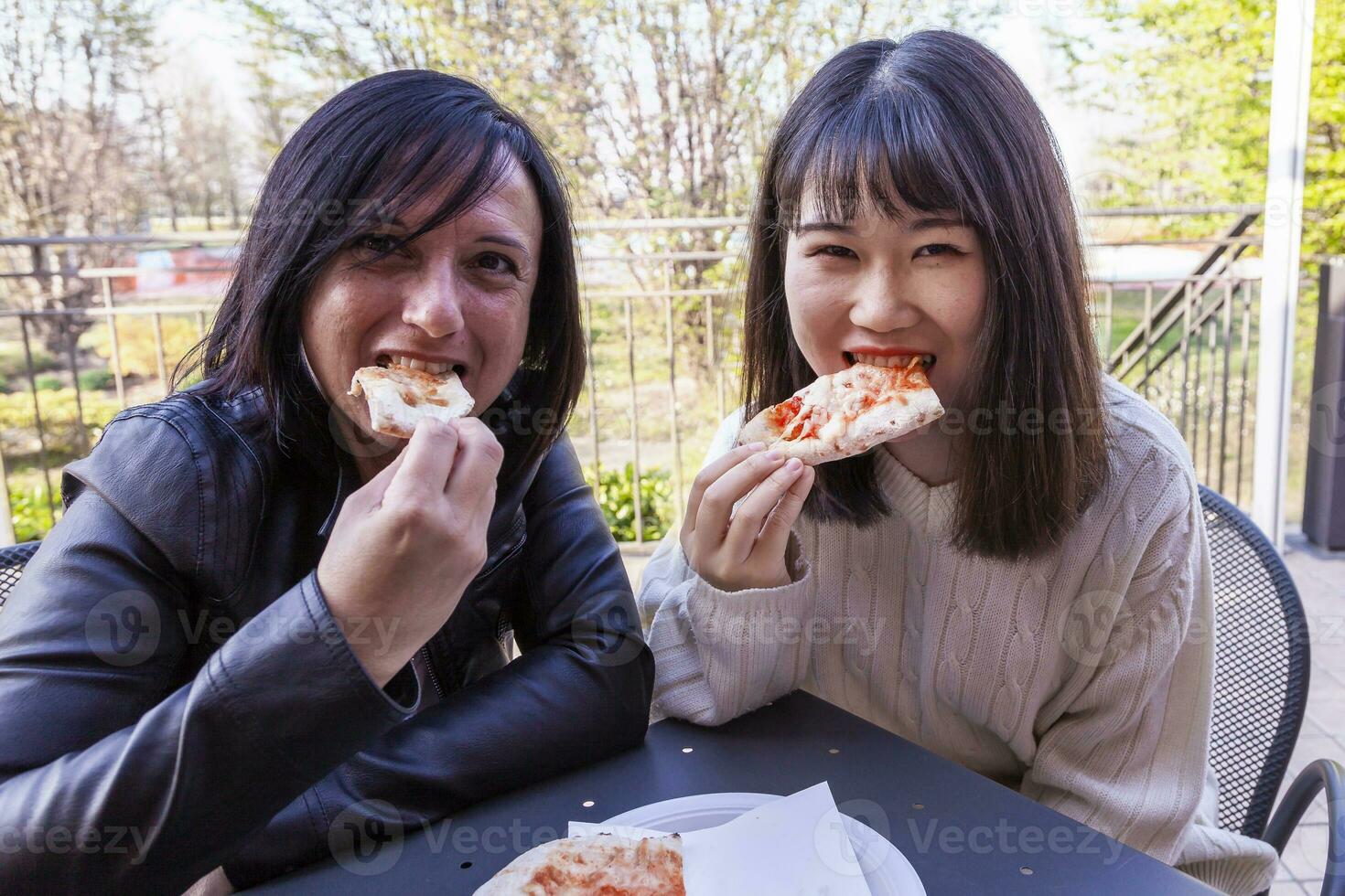 young girlfriends multi-ethnic females eating pizza photo