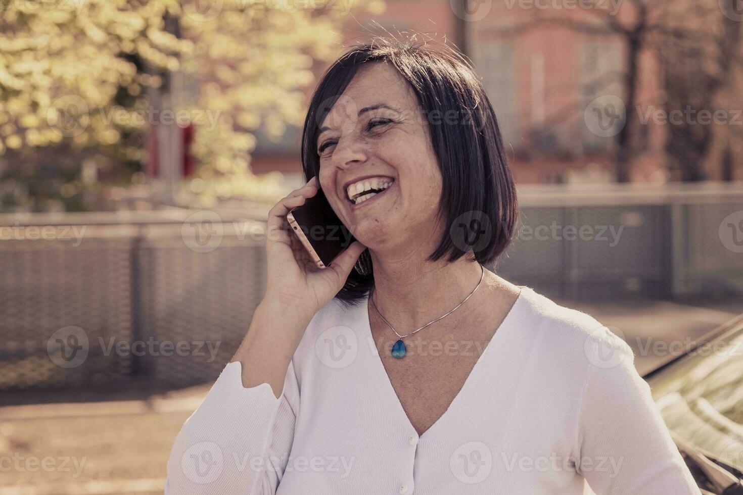 bonito mujer hablando y riendo a teléfono inteligente foto