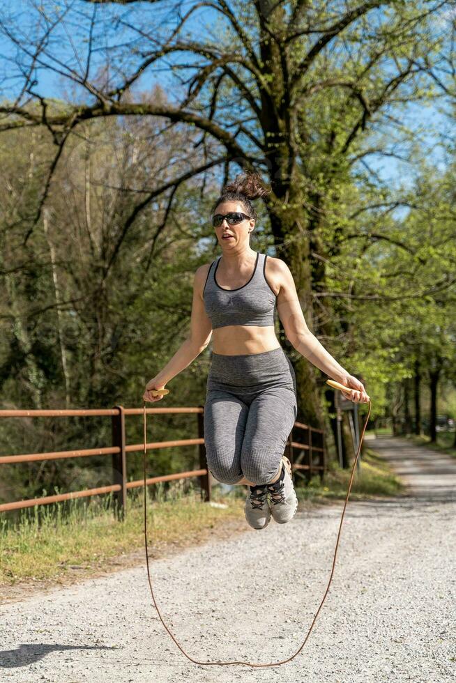 hermosa medio Envejecido mujer saltando cuerda al aire libre foto