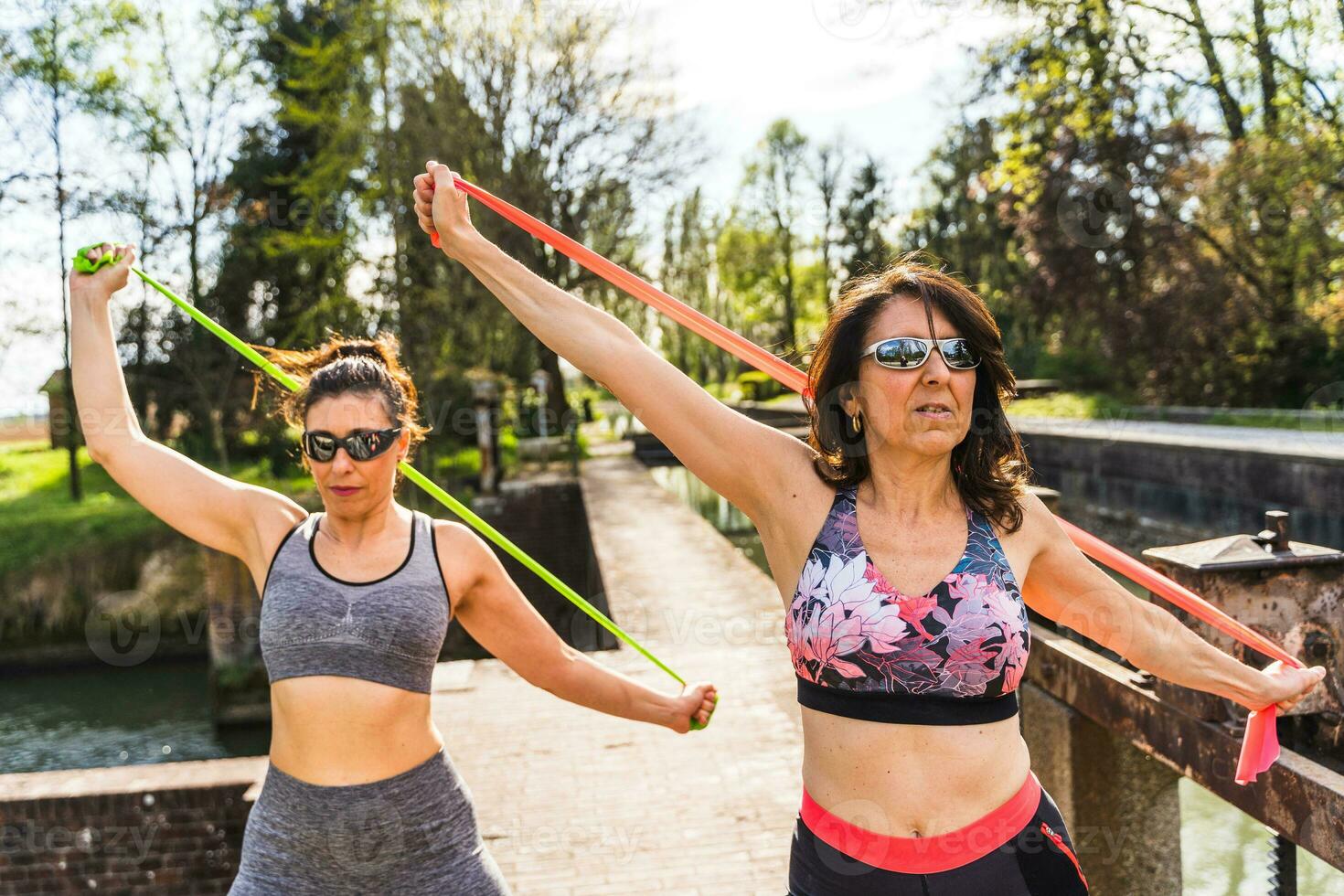 beautiful middle aged women doing exercises outdoors with a resistance band photo