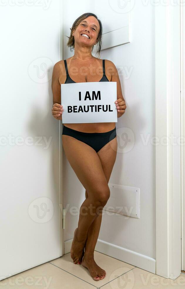 imagen de un hermosa medio Envejecido mujer posando en su Departamento - concepto acerca de cuerpo positividad yo estima y cuerpo aceptación foto