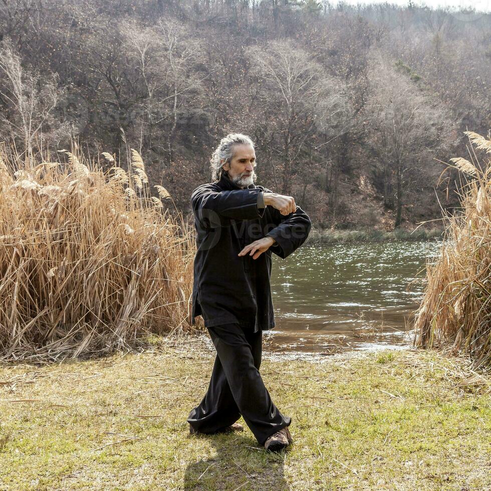 mature man practicing Tai Chi discipline outdoors photo