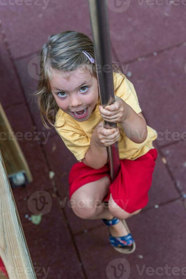 cute little girl have fun climbing a wooden structure in a playground photo