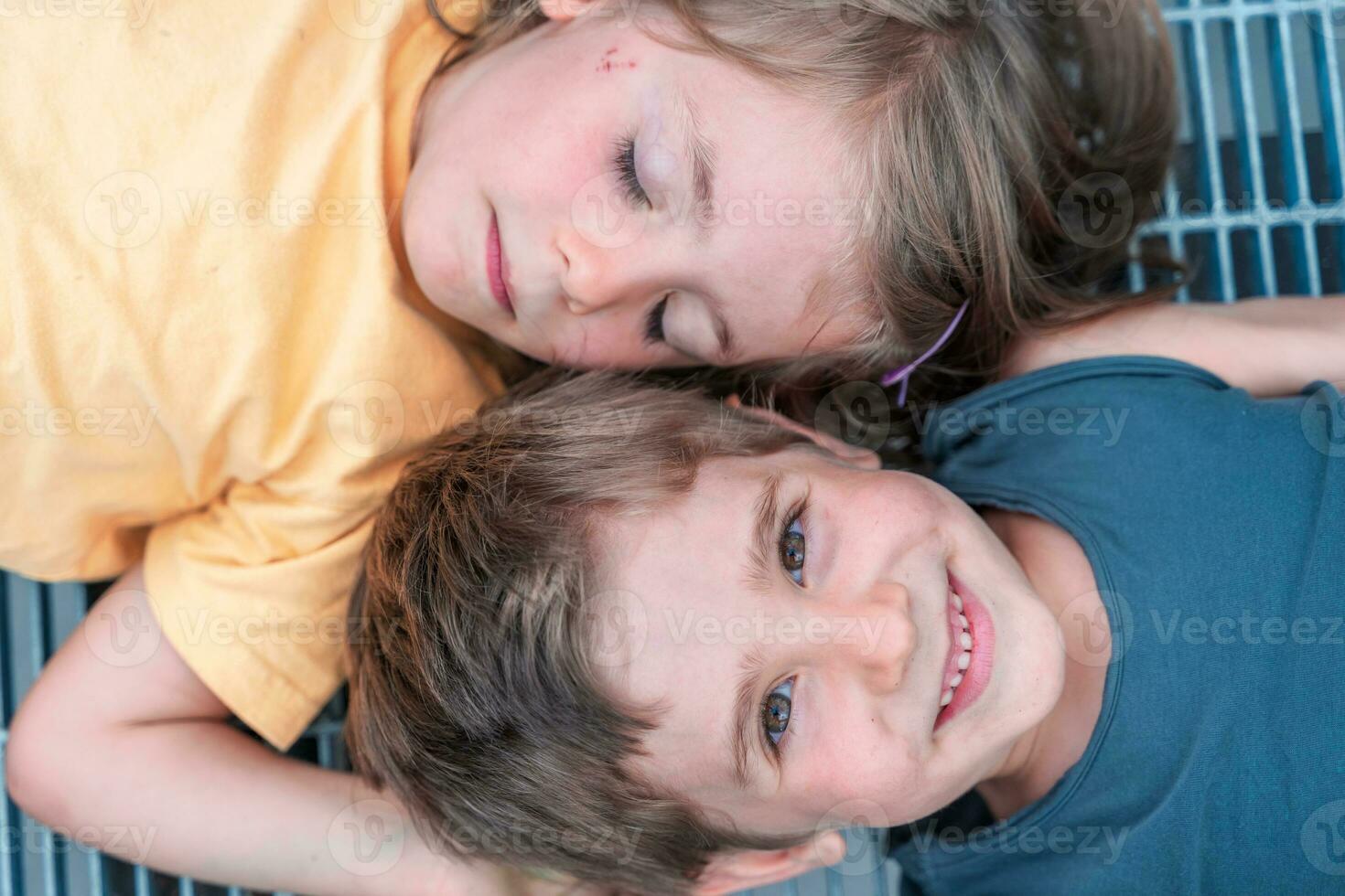 portrait of twins boys and girls lying on a metal grate photo