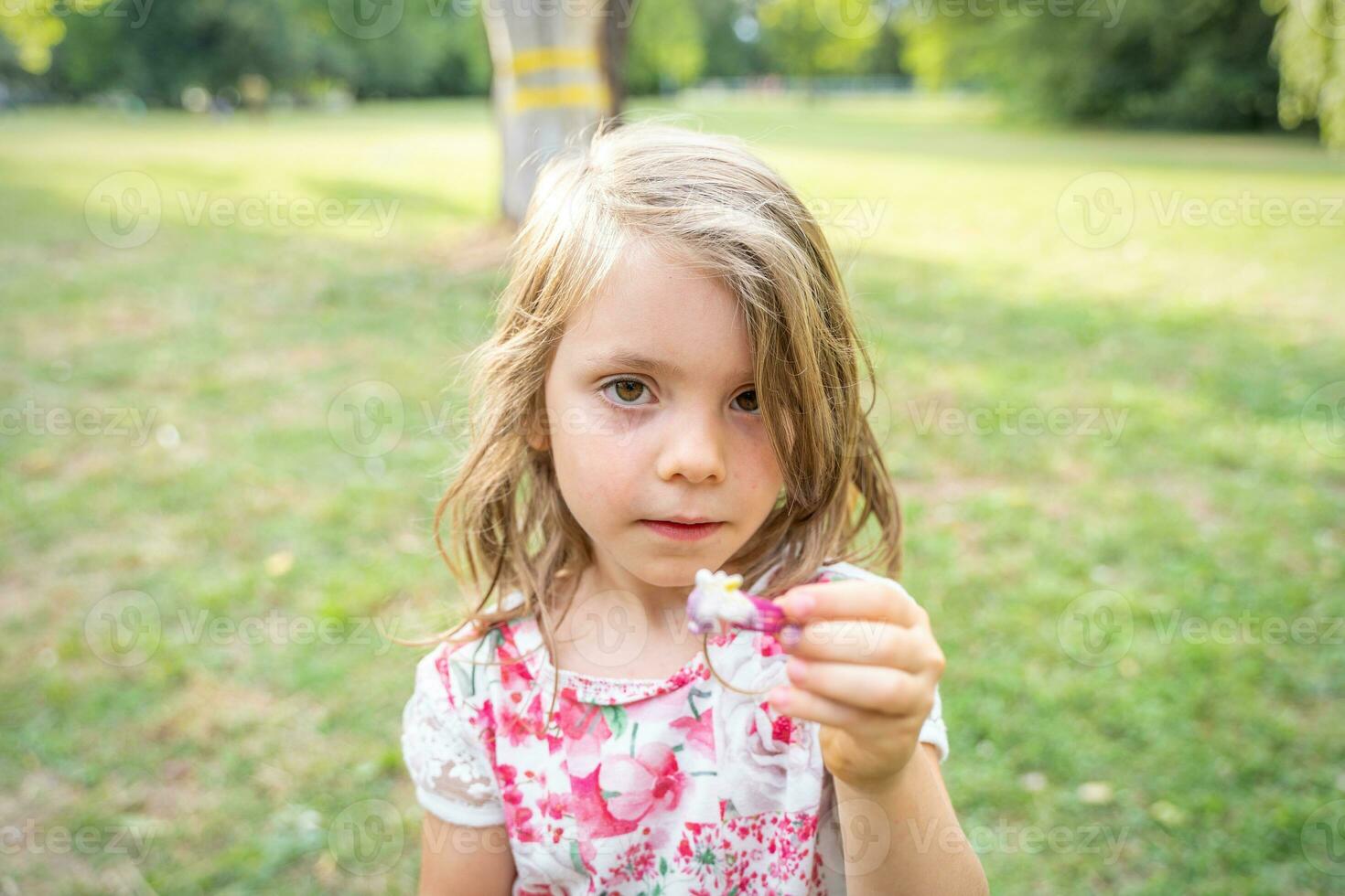 retrato de linda niña es demostración un pelo acortar en un público parque foto