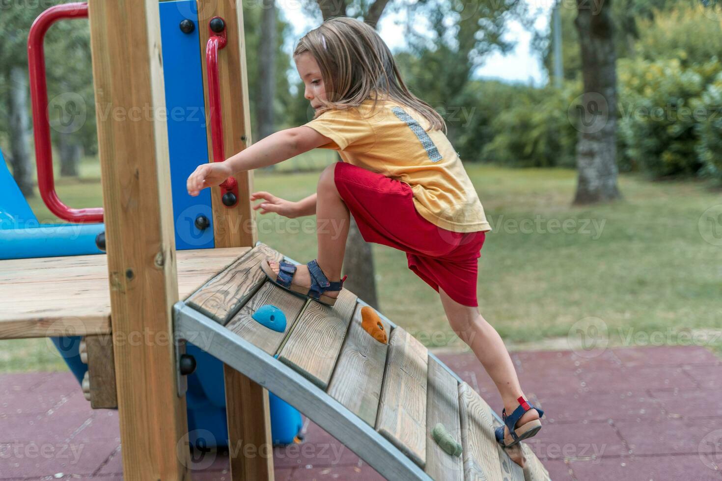cute little girl have fun climbing a wooden structure in a playground photo
