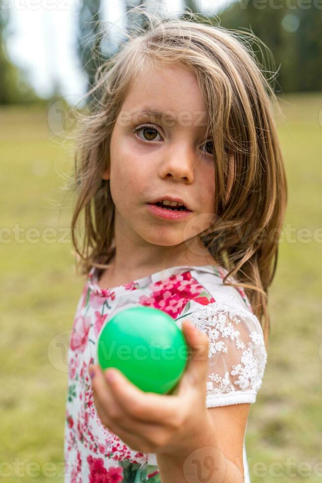 portrait of smiling cute little girl playing with an old tennis racket in a public park photo