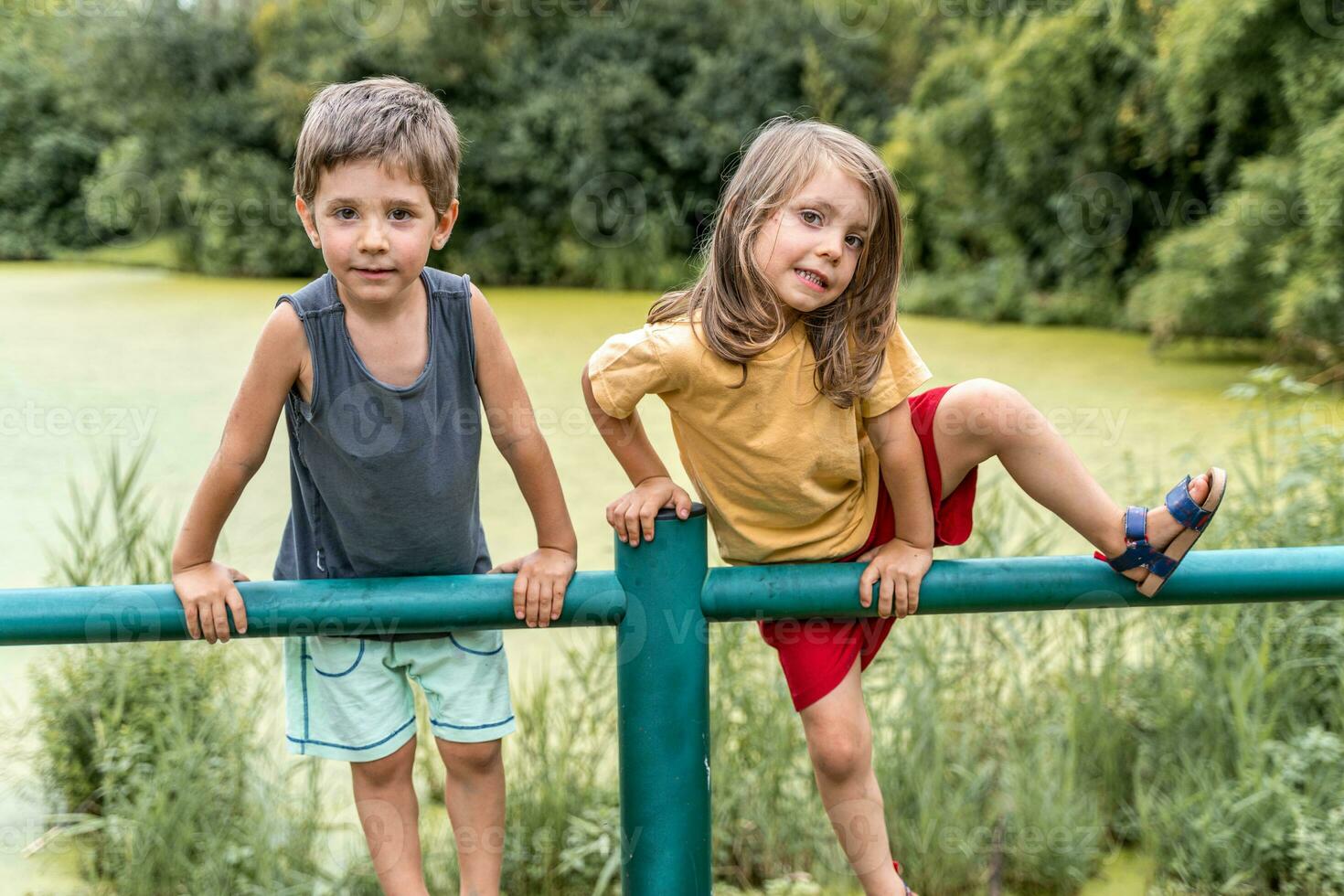 Gemelos Niños y muchachas tener divertido alpinismo metal tubería foto