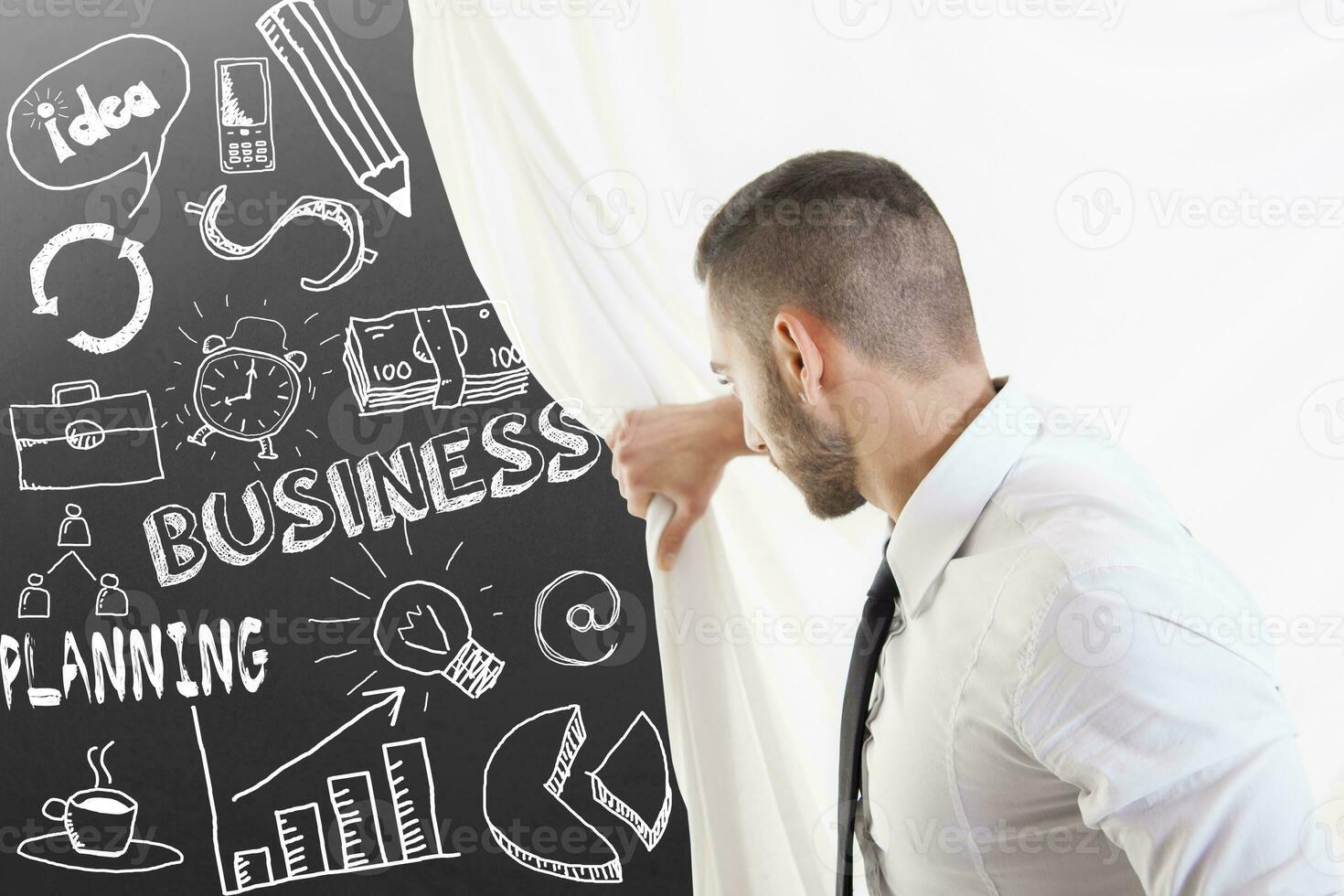young businessman looks at sketches of graphic symbols on the wall photo