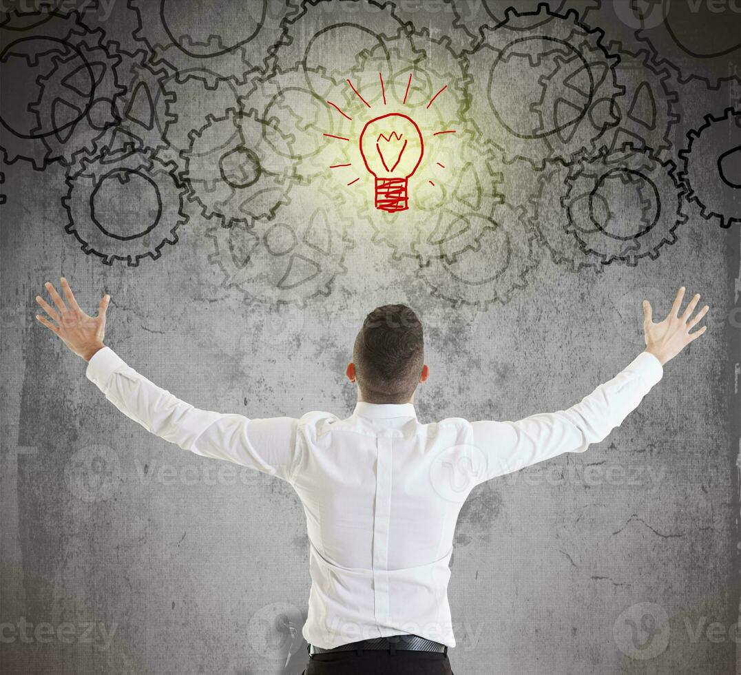 young businessman looks at gear symbols painted on the wall photo