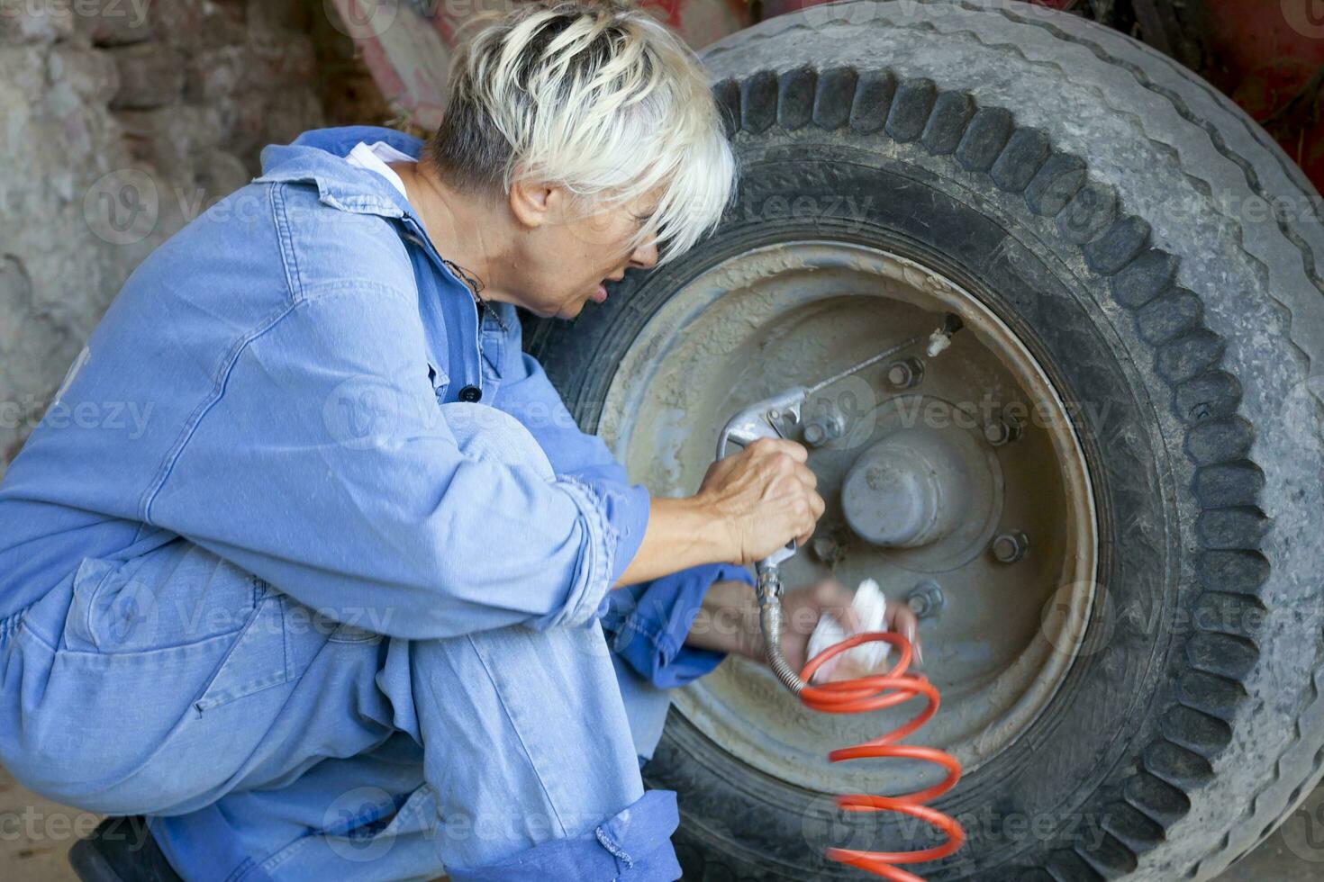 mechanical mature female inflates the tire of the tractor photo