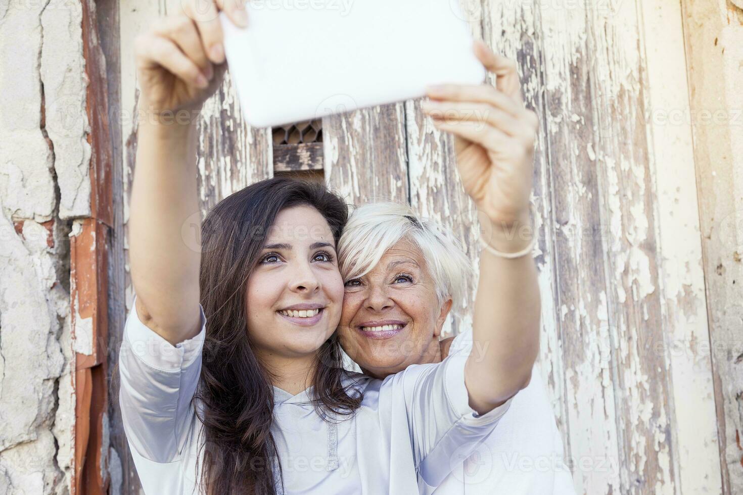 mother and adult daughter take a selfie outdoors photo