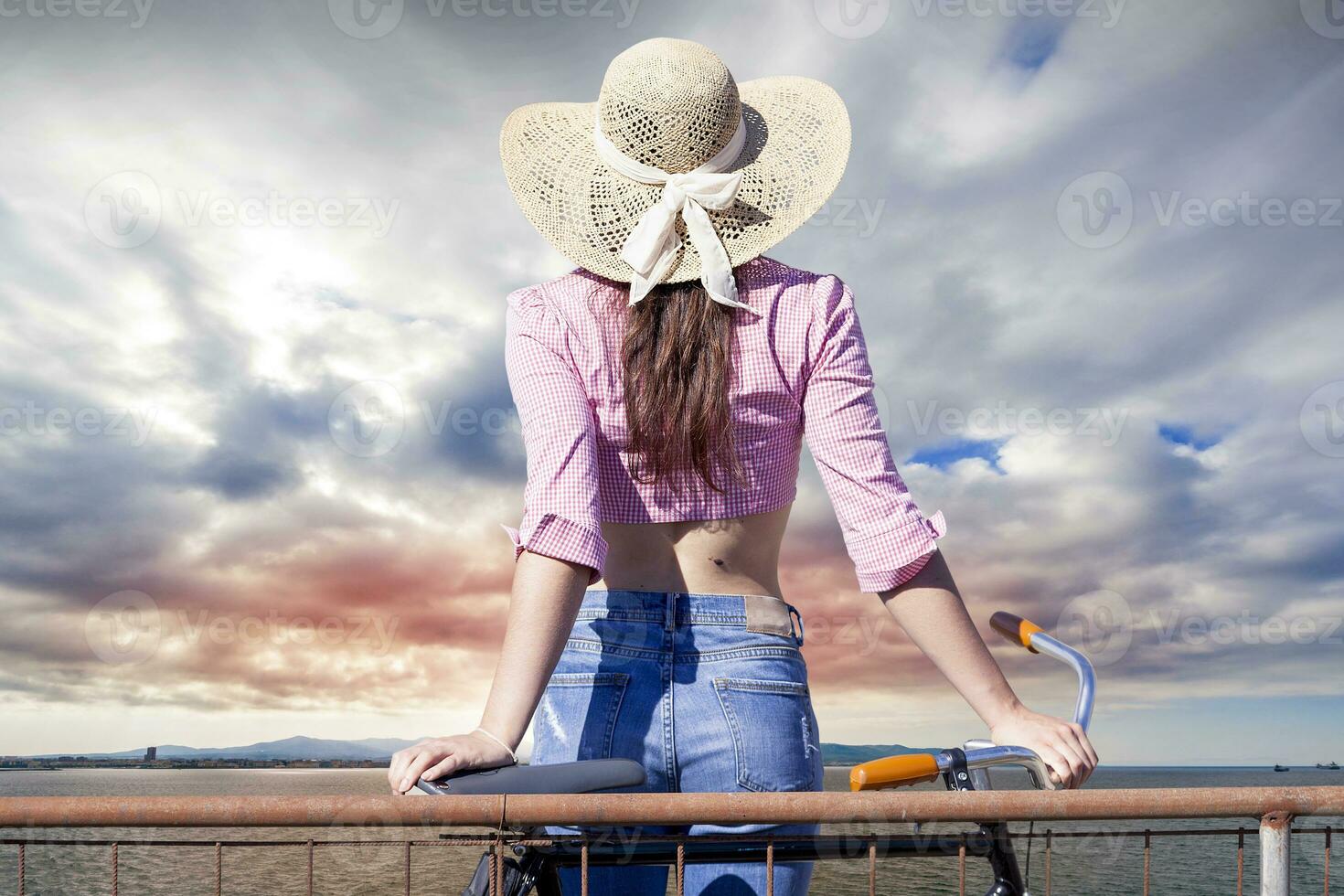 pretty girl with hat from the back looks at sea horizon photo