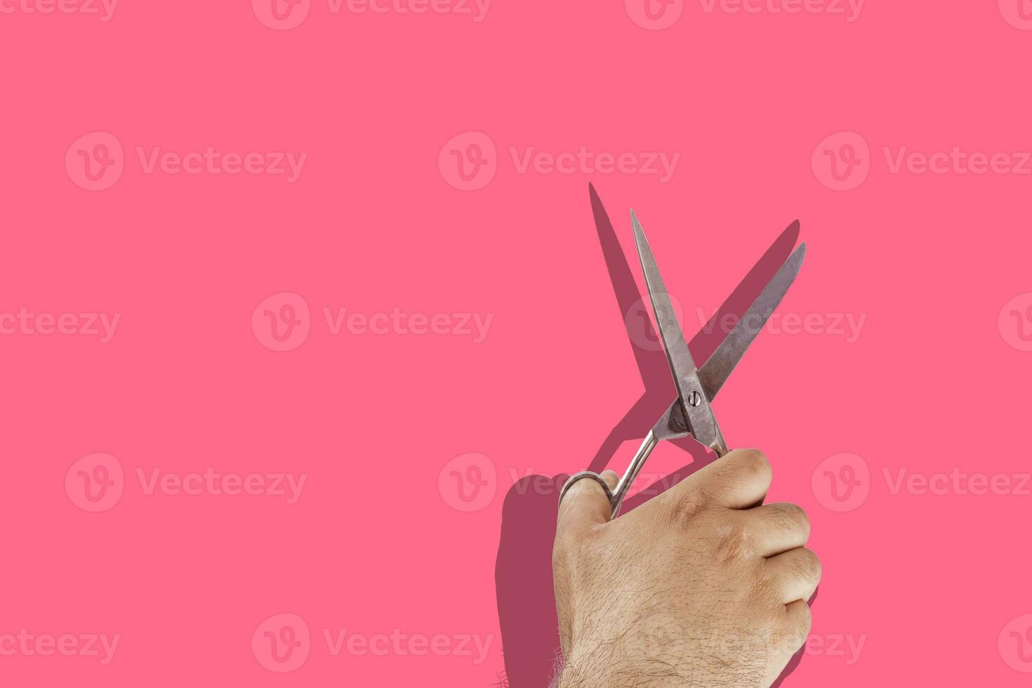 Hand with scissors on pink. Copy space for text or ads photo