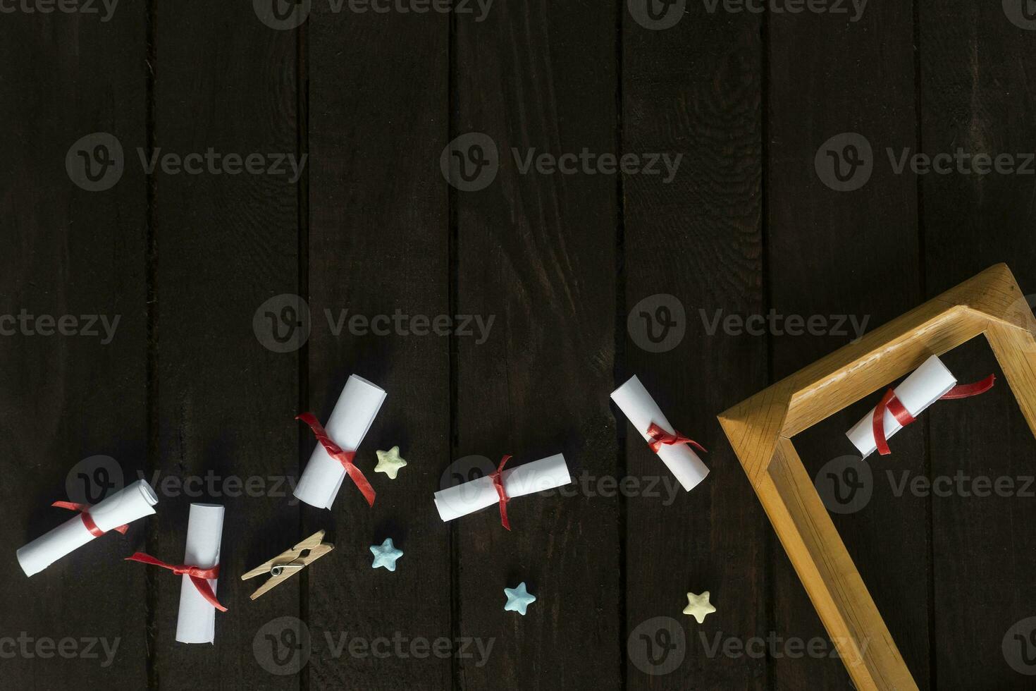 Flat lay romantic background. Giftbox, rolled wish papers, and wooden frame with paper hearts on dark wood board. photo