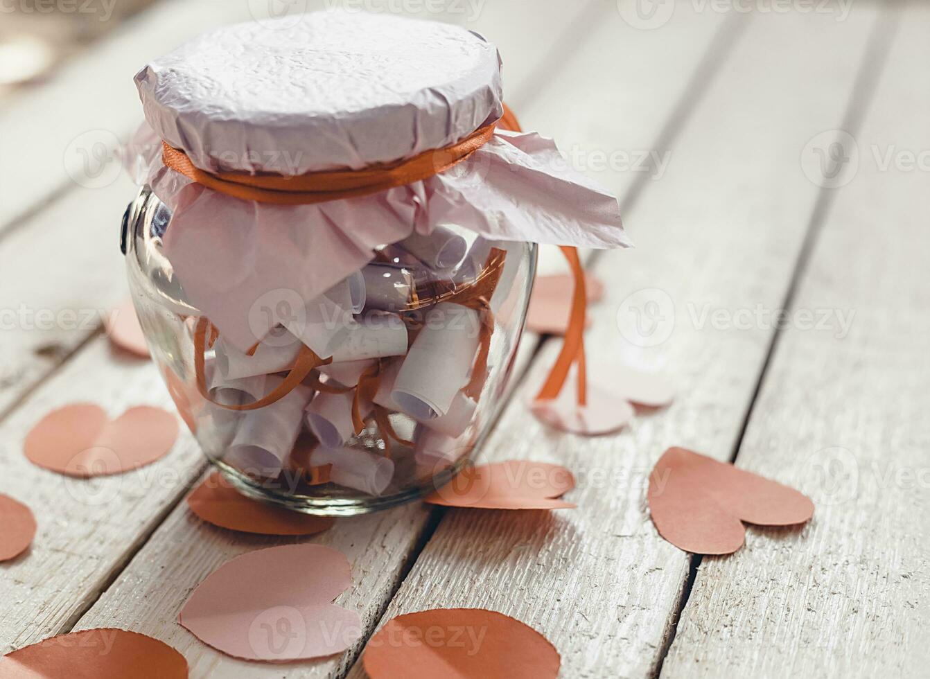 Glass jar on wood. Valentine's day concept. Date Jar with desires. Red paper hearts at background. photo