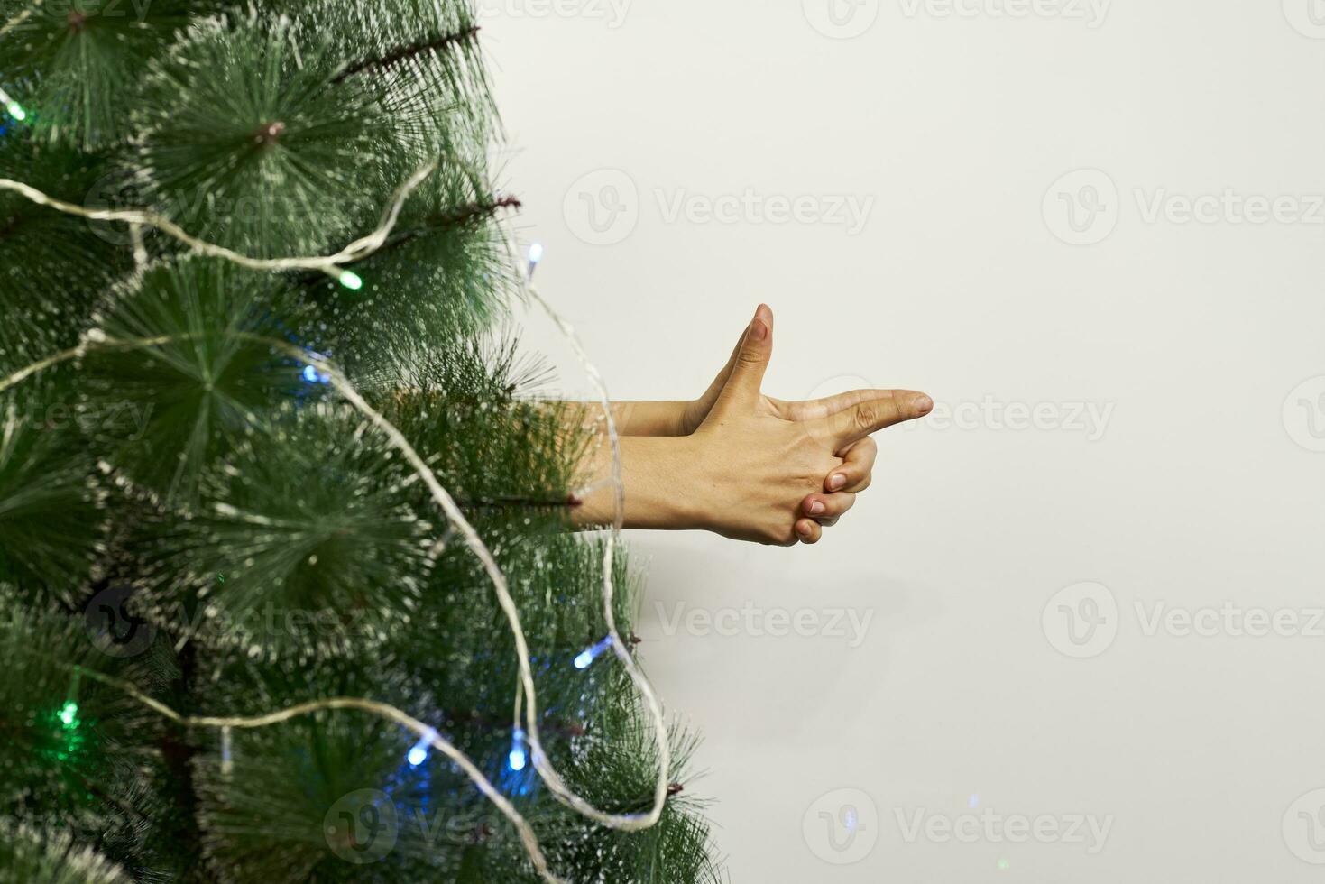 Hand pistol gesture behind the Xmas tree photo