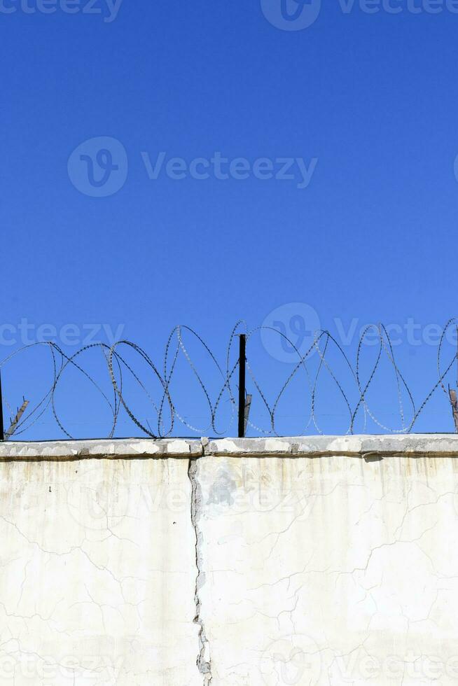 Jail wall. Highly protected prison wall with barbed wire fence photo