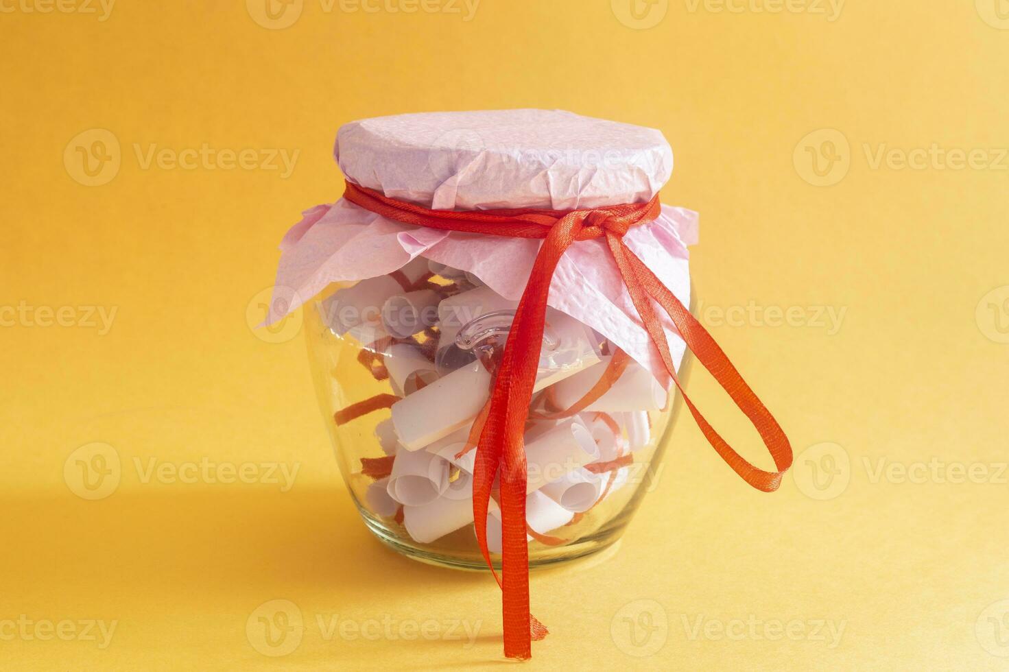 Desires, Wishes or Dreams written on rolled papers in glass jar on yellow photo