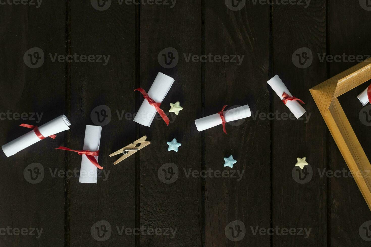 Flat lay romantic background. Giftbox, rolled wish papers, and wooden frame with paper hearts on dark wood board. photo