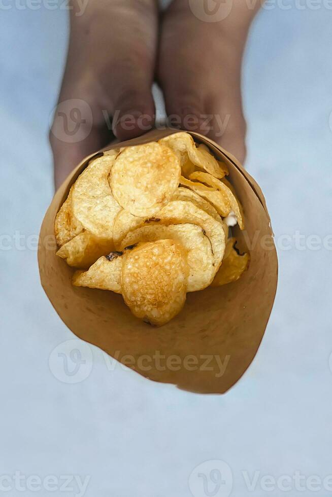 un papel cono lleno de patata papas fritas en el mármol foto