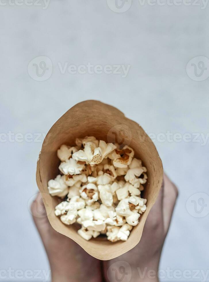 un papel cono lleno de palomitas de maíz en el mármol foto