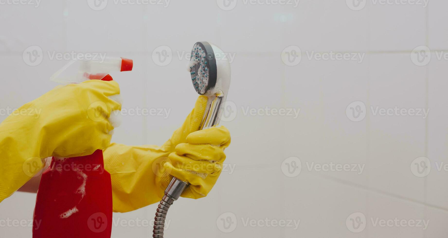 Woman in rubber gloves cleaning the shower head photo