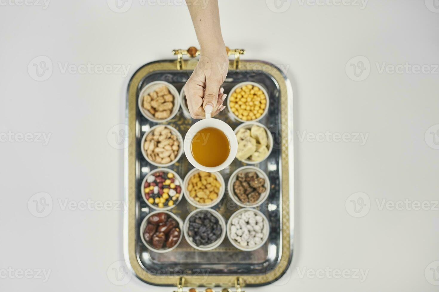 Woman hands holding a cup of tea over traditional arabic iftar sweets and snacks photo