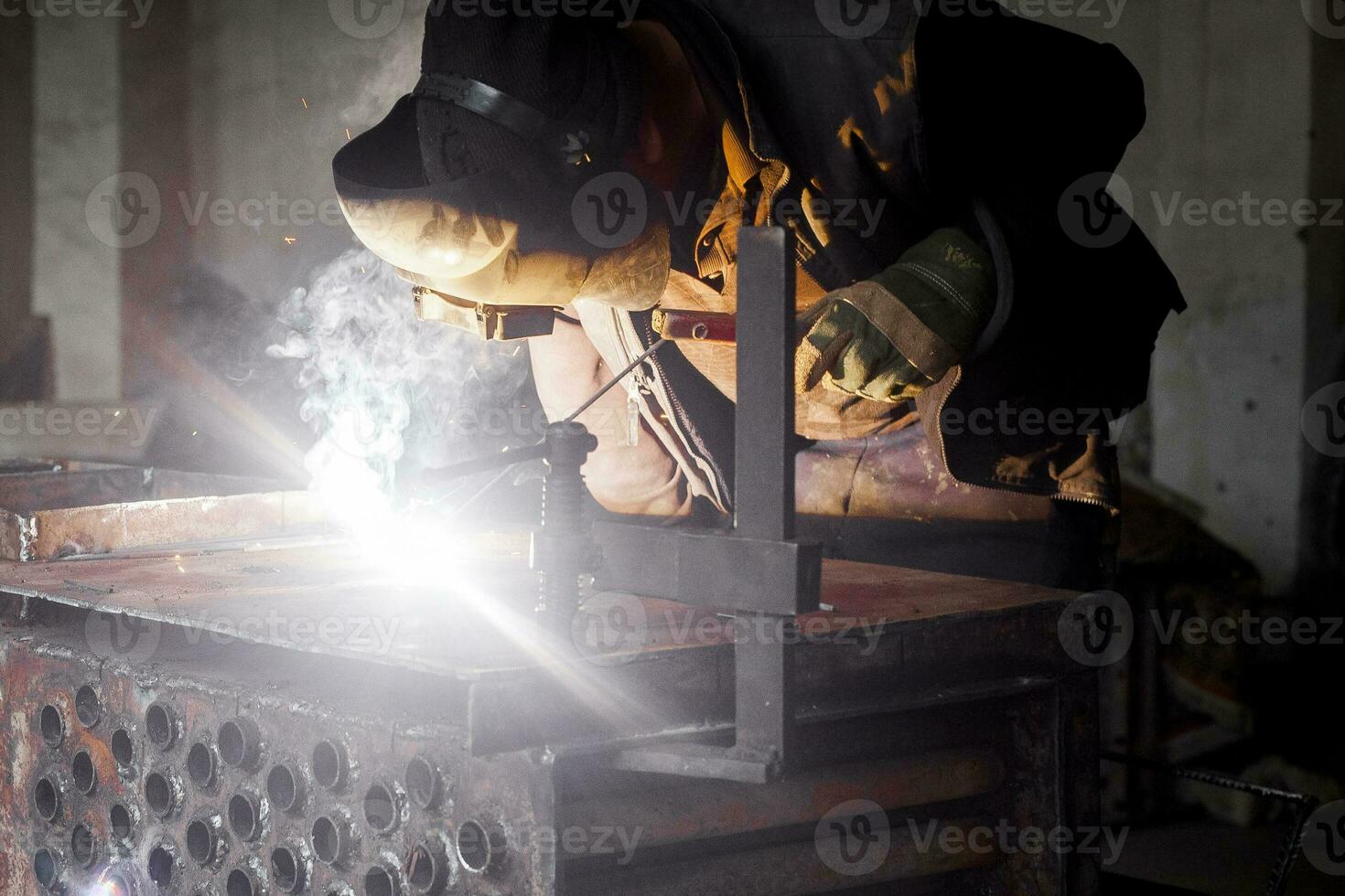 Man welds metal. Worker welding steel in industry with safety mask safety gloves and safety equipment. Metal industry welding concept photo