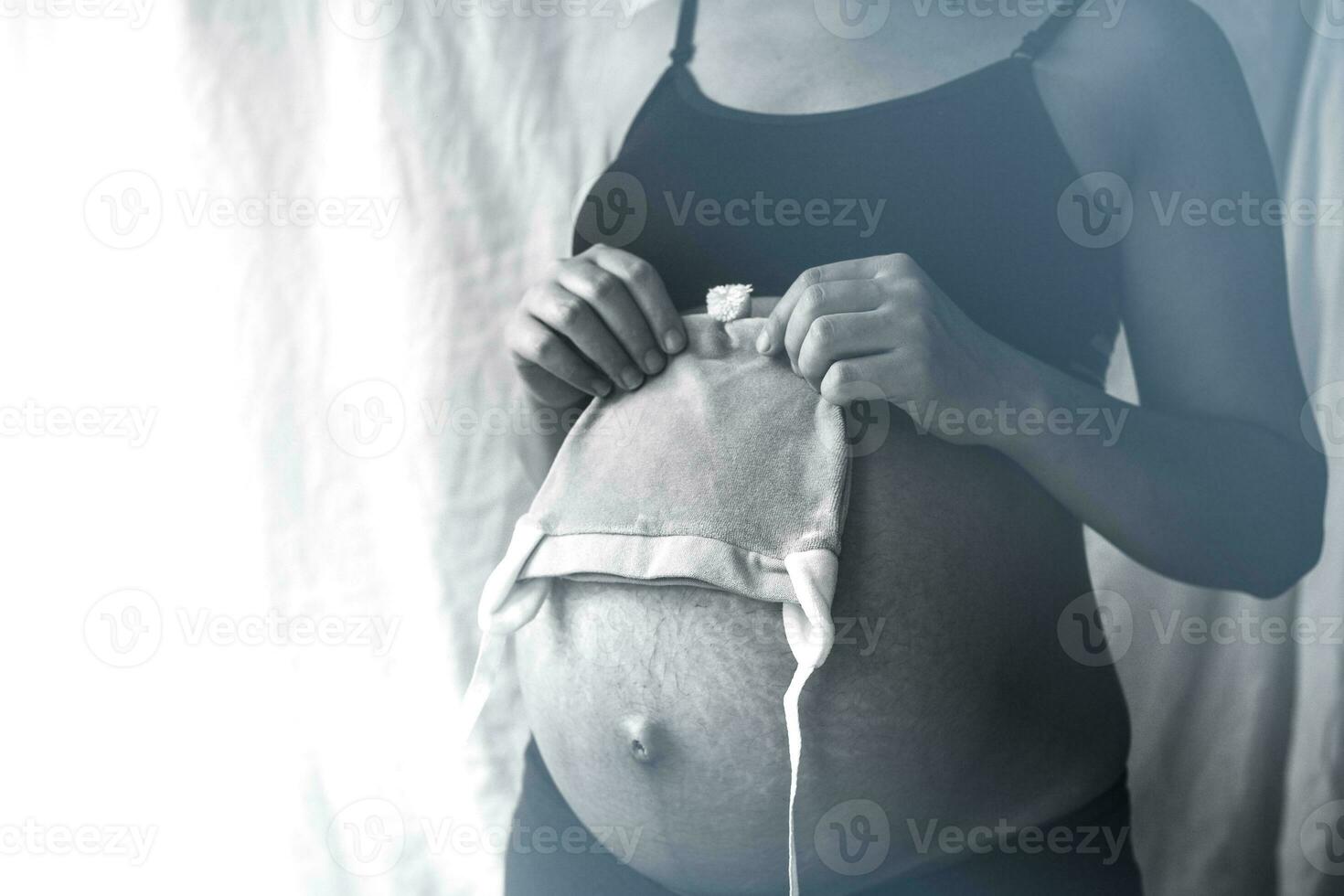Pregnant woman holding baby hat photo
