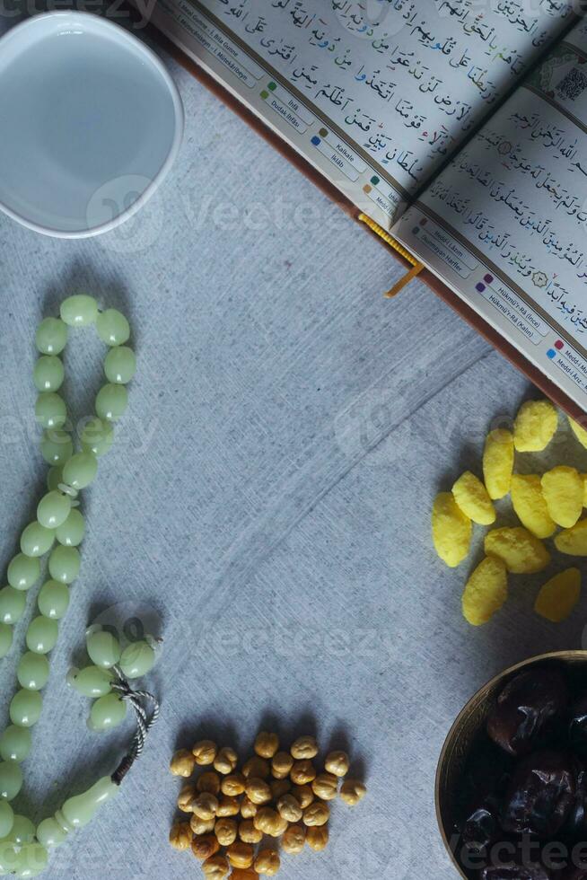 Holy Quran, Rosary, Iftar sweets and dried fruits with a cup of water. View from above. Flat lay photo