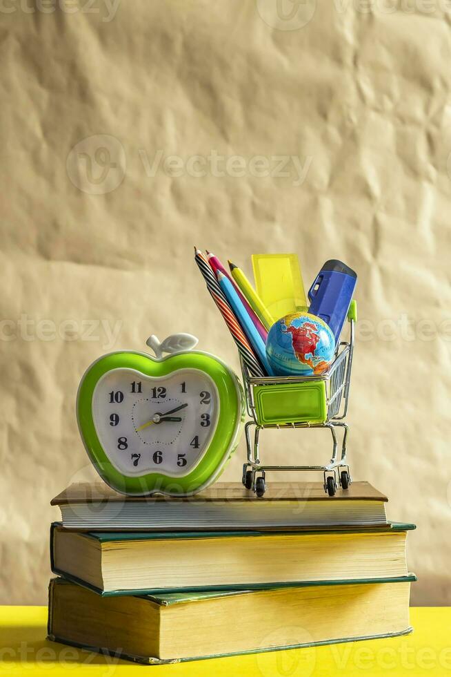 Back to school concept. Stack of books with school supplies in shopping cart photo