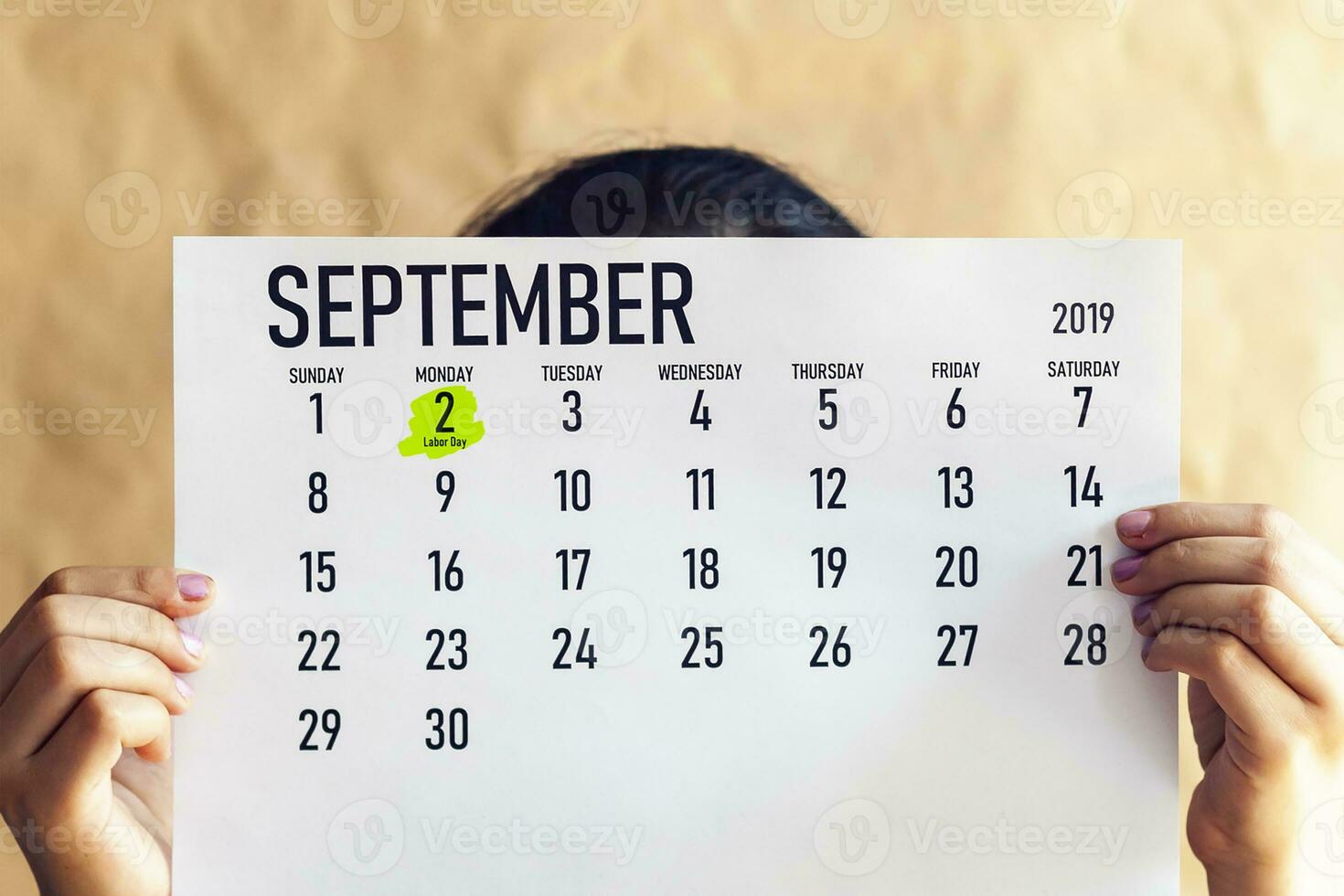 A woman holding August calendar with marked Labor Day. 2nd September marked at 2019 calendar photo