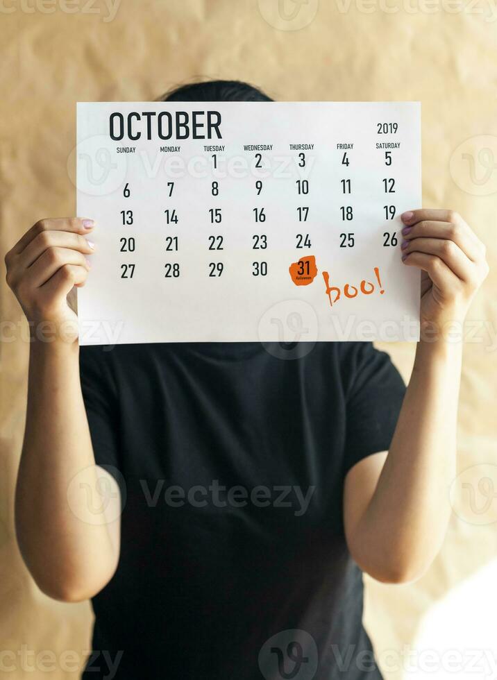 A woman holding August calendar with marked Halloween Day. 31st October marked at 2019 calendar photo