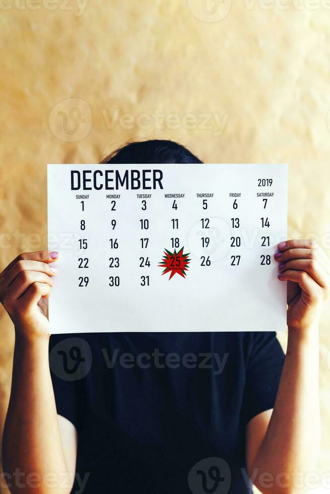 A woman holding calendar with Christmas day marked photo