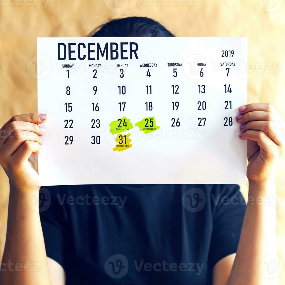 Woman holding December Calendar with marked holidays photo