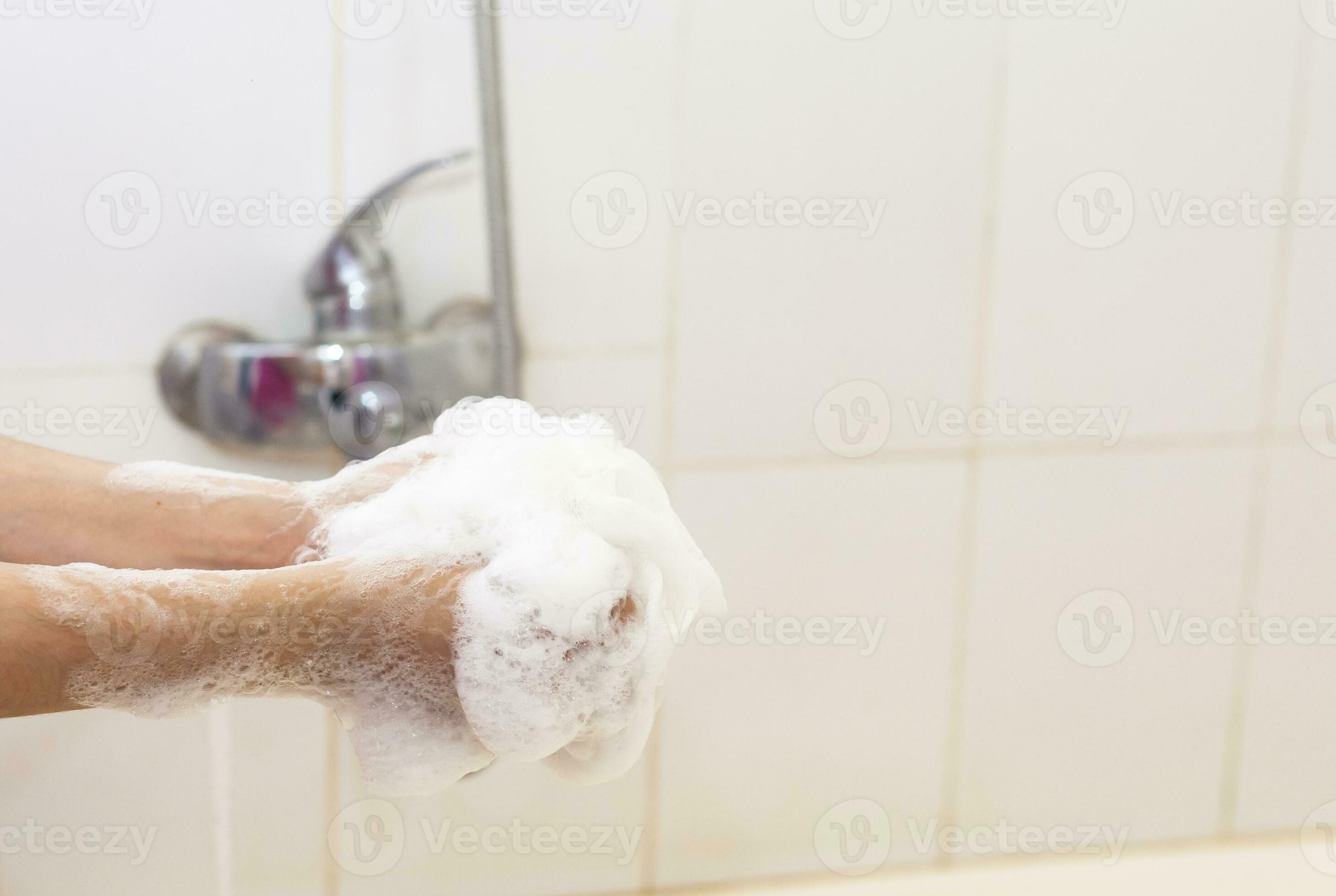 Woman washing hands with a sponge in the bathroom. Female washing arms