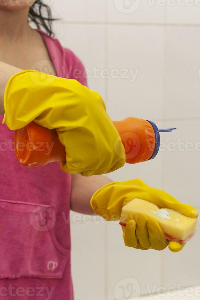 Young woman equipped with chemical cleaner bottle and sponge. Housekeeping and cleaning concept. Women preparing to clean up bath photo